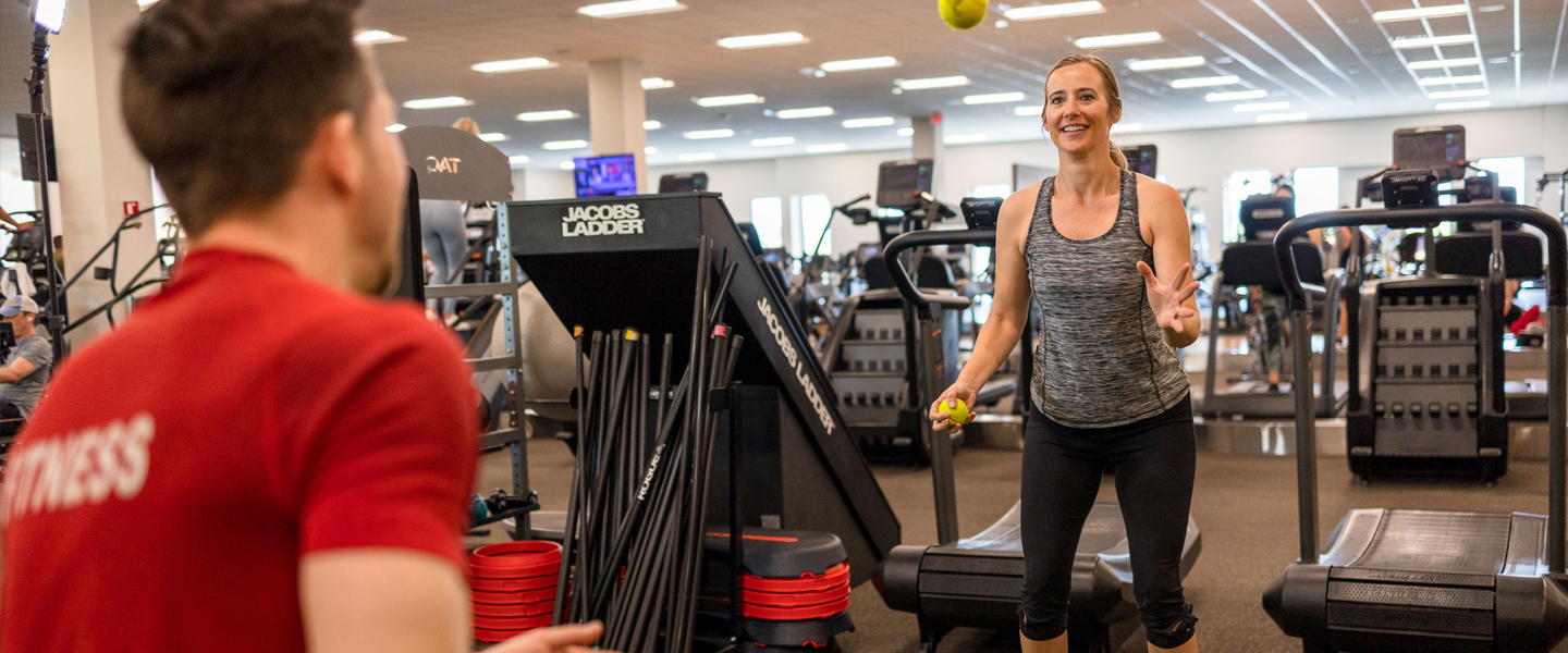 Personal Trainer throwing tennis balls to a member balancing